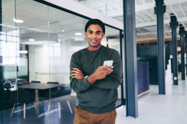 istock Creative young businessman holding a smartphone in a modern office 1382272970