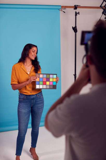 istock Mature Female Model Posing Against Background On Studio Shoot Holding Colour Checker Card For Video 1382273093