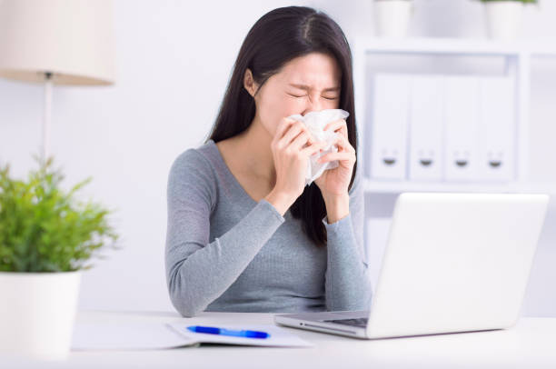 Jeune femme stressée qui éternue et travaille au bureau à domicile - Photo