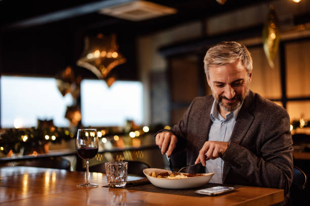 istock Happy caucasian man, checking on his phone, while eating dinner at an eatery. 1382274914
