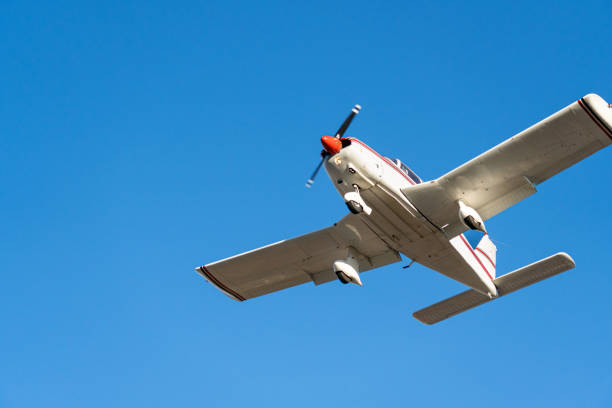 Small plane flying in a clear blue sky turning to land
