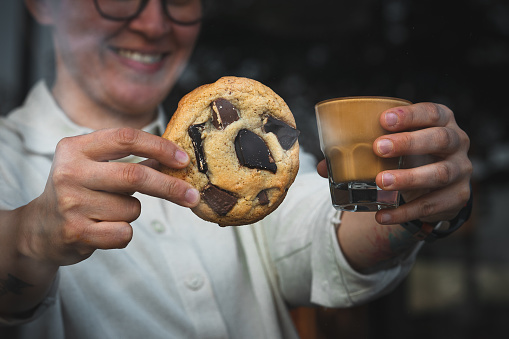 Woman holding cookie and coffee at cafe