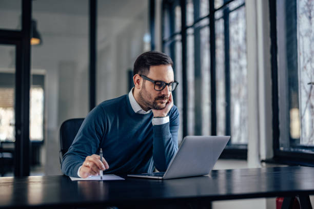 istock Serious caucasian insurance salesman, checking his client status, on his laptop. 1382276206