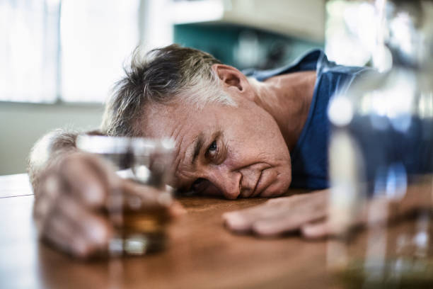 hombre de mediana edad bebiendo licor fuerte en casa durante el día - alcohol alcoholism addiction drinking fotografías e imágenes de stock