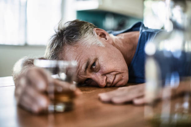 uomo di mezza età che beve superalcolici a casa durante il giorno - alcohol alcoholism addiction drinking foto e immagini stock