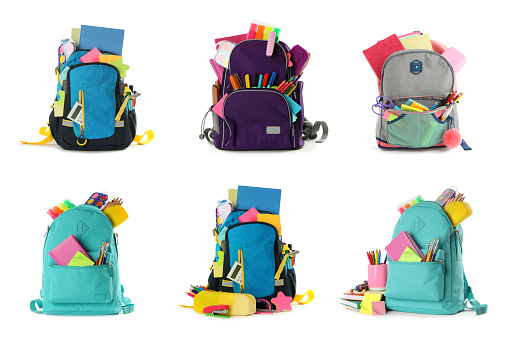 Set of backpacks with bright school stationery on white background