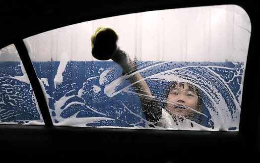 Asian girls learning how to wash a car for their father.