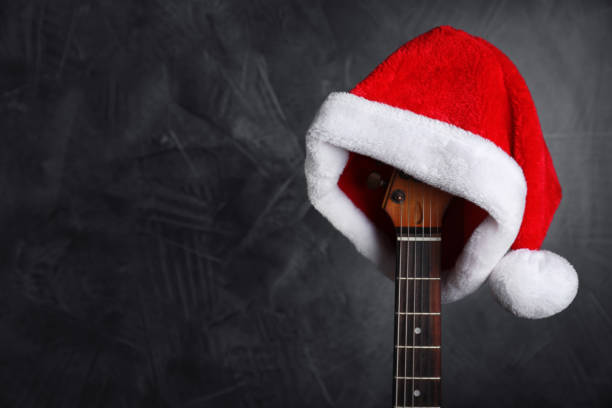 istock Guitar with Santa hat on black background, space for text. Christmas music 1382277507