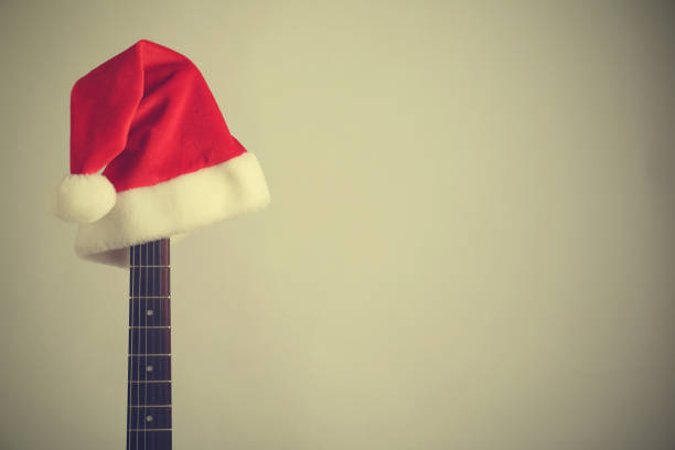 istock Guitar with Santa hat on light background, space for text. Christmas music 1382277517