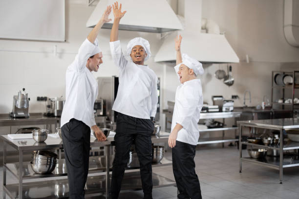 istock Multiracial team of chefs taking hands together before a job on kitchen 1382278203
