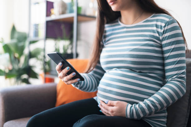 istock Pregnant woman using smart phone at home. 1382278238