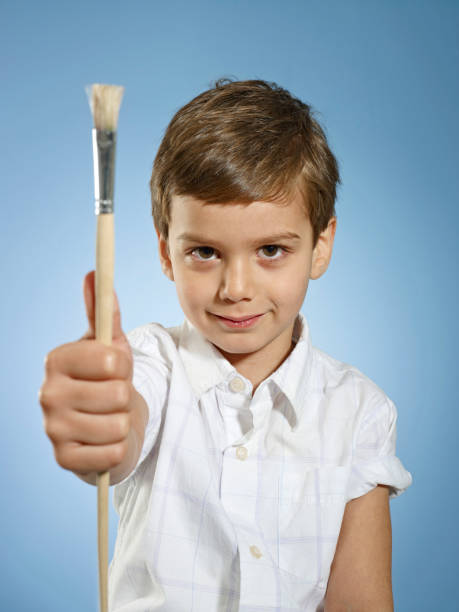 Little boy holding paintbrush.