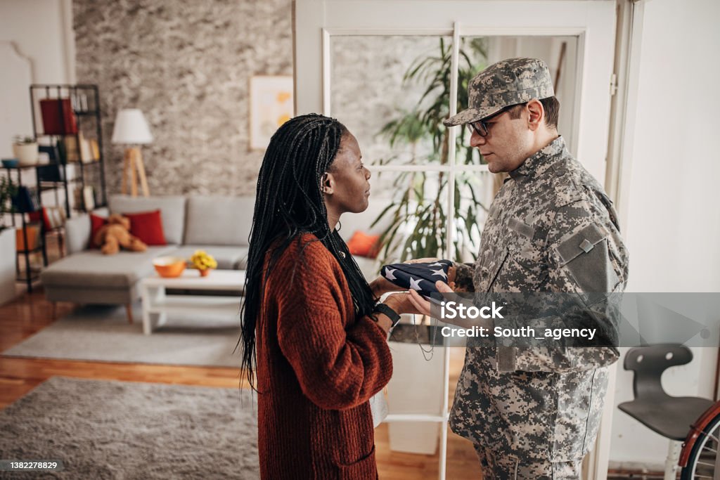 Soldier bringing folded American flag to widow at home, to say her that she has lost her husband in the army war American Flag Stock Photo