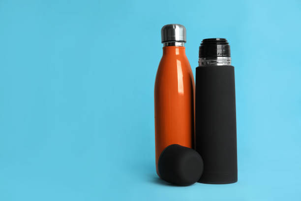 istock Stylish thermo bottles on light blue background, space for text 1382285851