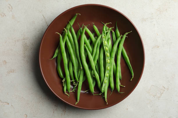 istock Fresh green beans in bowl on light grey table, top view 1382287048