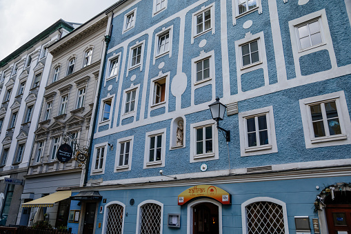 Linz, Austria, 27 August 2021: Narrow picturesque street, Facade of colorful buildings in historic center of medieval city, renaissance and baroque houses at summer sunny day, cafe with wooden windows