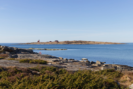 Halmstad, Halland, Sweden - March 4, 2022: Image was taken in the midday of 4th March 2022, in the costal region of Tylösand. Image presents rocky coast of western Sweden. There is a island of Tylön with recognizable lightohouse in the background. No people. Sunny day. Travel destination.