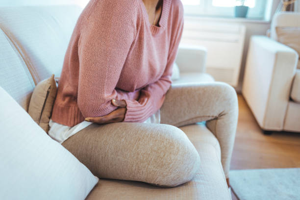 cropped shot of an attractive young woman lying down on her bed and suffering from period pains at home. - stomachache illness pain indigestion imagens e fotografias de stock