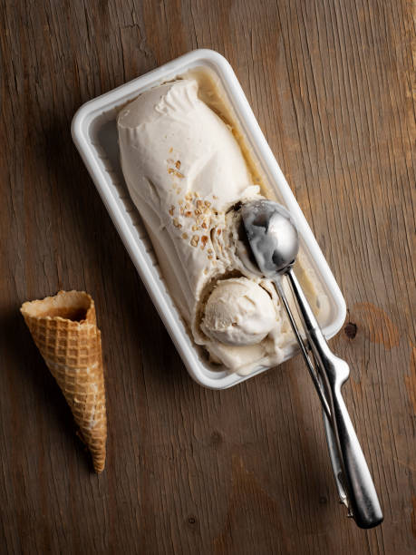 ice cream, Tahini ice cream, Metal scoop scrapes vanilla ice cream from the box stock photo