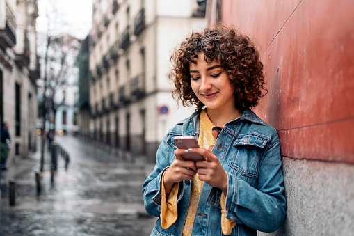 Stock photo of pretty girl standing in the street using her smart-phone.