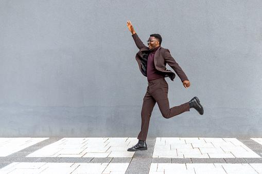 Energetic young man businessman jumping outdoors