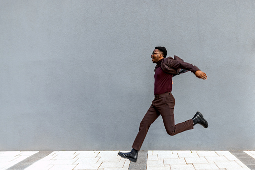 Full length profile shot of a young businessman jumping in the air