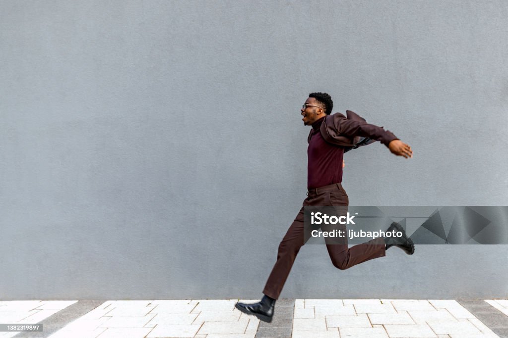 A male businessman jumping in the city Full length profile shot of a young businessman jumping in the air Jumping Stock Photo