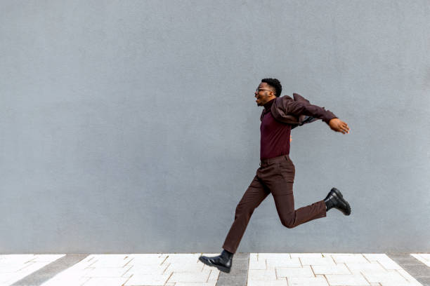 мужчина-бизнесмен прыгает по городу - people well dressed success achievement стоковые фото и изображения