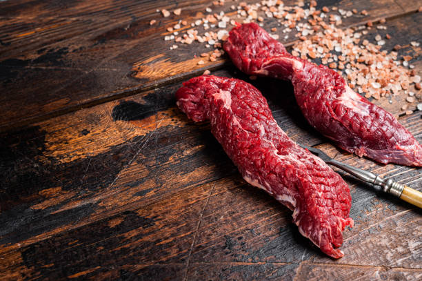 Uncooked raw Machete skirt steak on meat fork. Wooden background. Top view. Copy space