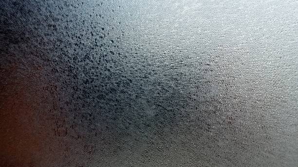 istock Abstract frosty pattern on glass, background texture. Frozen windshield. Granular structure of transparent ice. The sky is shining through. Abstract ice background. 1382332577