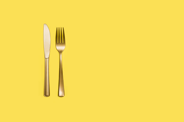 istock Golden plastic fork and knife on a yellow background 1382332638