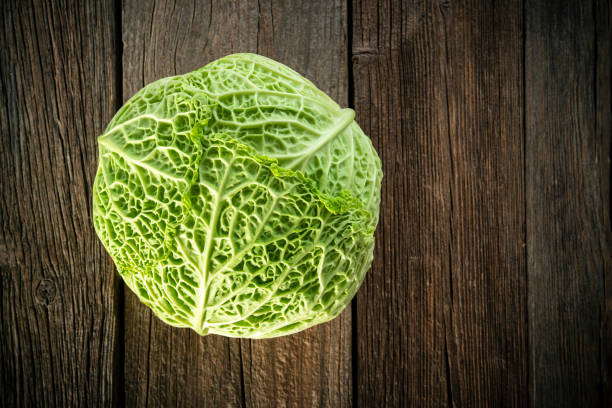 Savoy Cabbage crucifer raw leaf vegetable closeup on rustic wood board background
