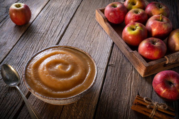 Apple sauce or apple pureed compote homemade with red apples crate box on rustic wood Apple sauce or apple pureed compote homemade with raw red apples crate box on rustic wooden table board with cinnamon sticks apple compote stock pictures, royalty-free photos & images
