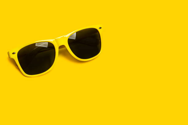 Yellow sunglasses on a yellow background with copy space