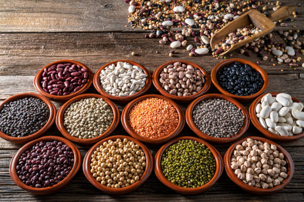 istock Assorted legumes in round clay containers on rustic wooden background with serving scoop 1382353553