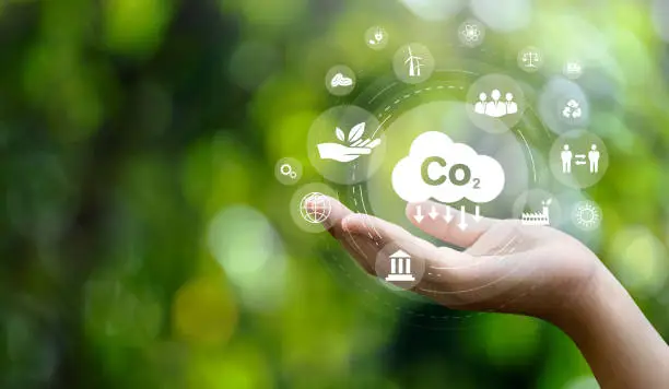 Photo of CO2 emission reduction concept in hand with environmental icons, global warming, sustainable development, connectivity and renewable energy green business background.