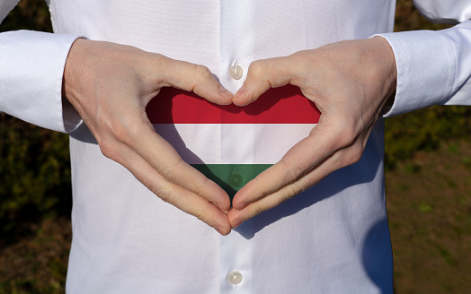 man holidng his hands in heart shaped on white shirt with hungarian flag tricolor colors symbol of the hungarian national day 15th of march .