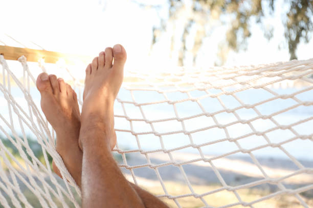 uomo che si rilassa sull'amaca sulla spiaggia, primo piano. vacanze estive - hammock beach vacations tropical climate foto e immagini stock