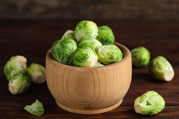 istock Bowl with fresh Brussels sprouts on brown wooden table, closeup 1382360872