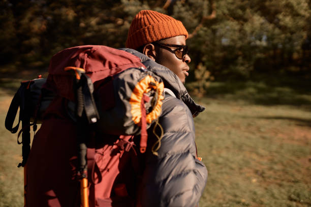 jeune touriste masculin errant dans la forêt, perdu dans la nature. l’homme apprécie l’activité de plein air avec sac à dos, se reposer sur l’air frais. temps d’aventure, voyage, exploration du monde, loisirs actifs, concept de faune - traveling light photos et images de collection