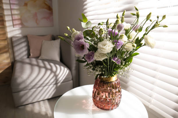 istock Bouquet of beautiful Eustoma flowers on table in room. Space for text 1382374734