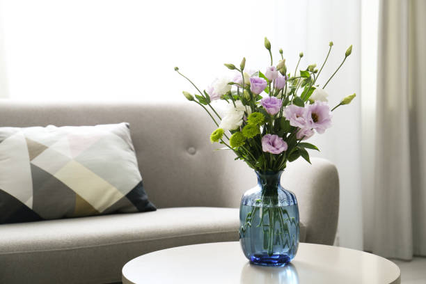 istock Bouquet of beautiful Eustoma flowers on table in room. Space for text 1382374832