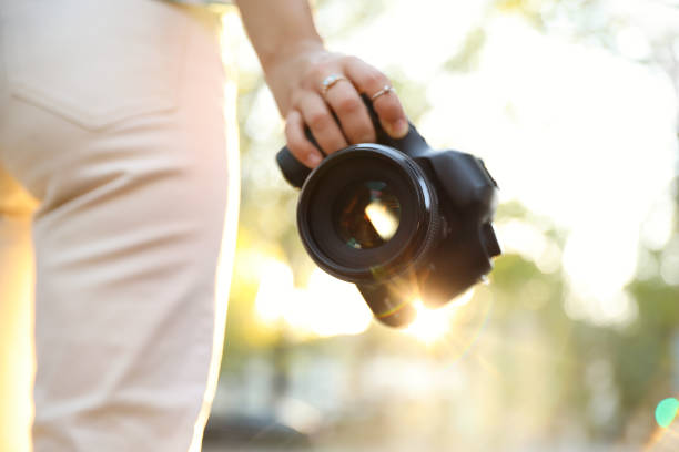 Young photographer with professional camera outdoors, closeup
