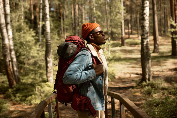 istock Astonished black man enjoy scenery from wooden bridge, backpack with stuff for camping. Bright emotions, new experience, explore horizons. Forest, youth, wildlife, hiking, contemplating life concept 1382378539