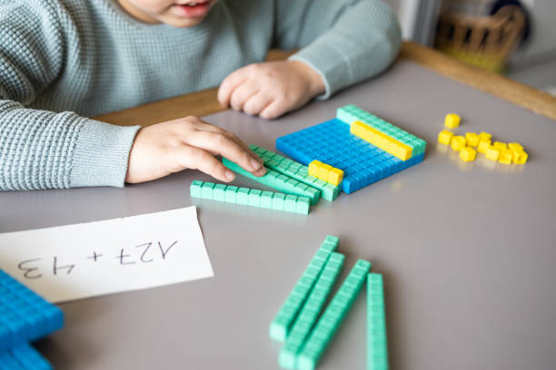 Little boy using the base 10 method to do addition at home