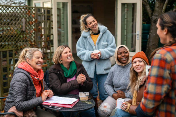 Volunteers Planning their Next Project Volunteers sitting outdoors wearing warm casual clothing on a sunny cold winters day. They are resting and having a tea break from working on a community farm, looking after crops and performing other sustainable and environmentally friendly tasks. They are laughing and talking together, drinking hot drinks. women issues stock pictures, royalty-free photos & images