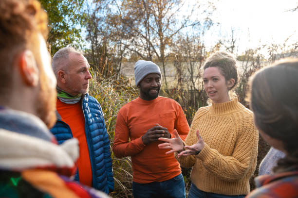 Volunteering on a Farm A multiracial group of volunteers wearing warm casual clothing and accessories on a sunny cold winters day. They are talking before they start working on a community farm, planting trees and performing other tasks. green environment friendly stock pictures, royalty-free photos & images