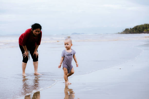istock grandmother watching baby when walking on the beach 1382390699