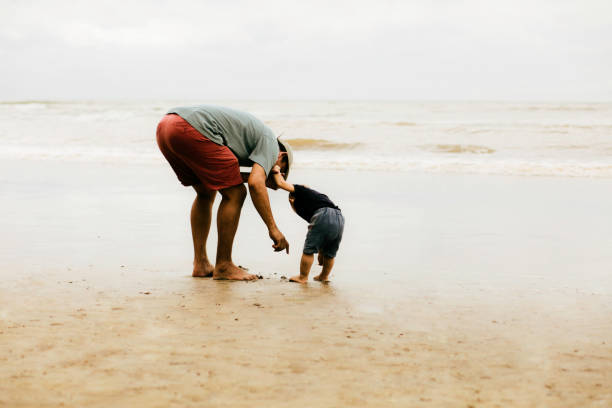 istock asian man teaching his baby walking on the beach 1382390721