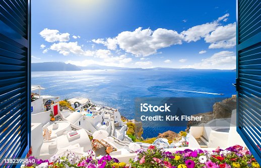 istock View through an open window with shutters of the whitewashed village of Oia rising above the blue Aegean Sea and the caldera on the island of Santorini, Greece. 1382395840